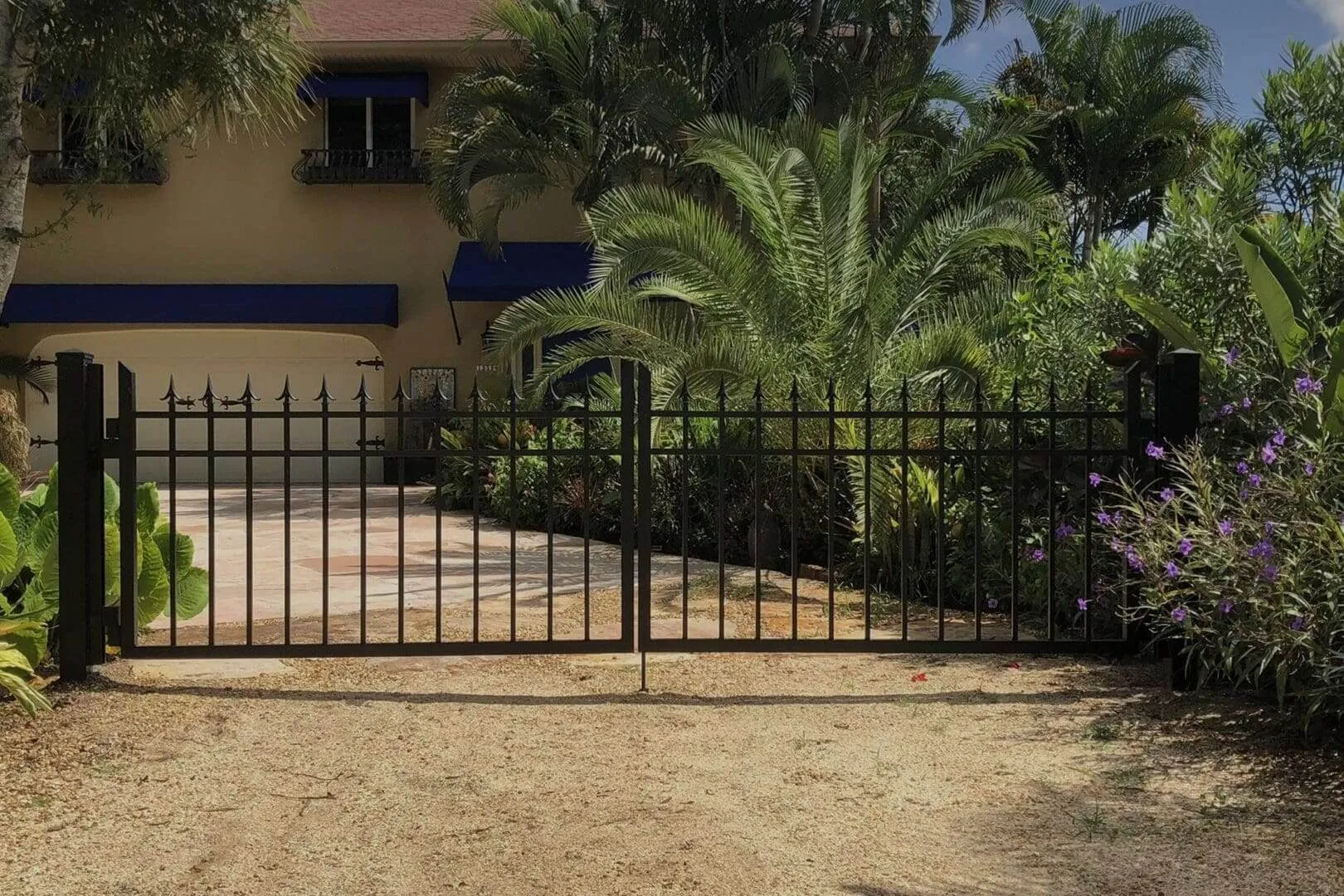 Lush driveway with black metal gate