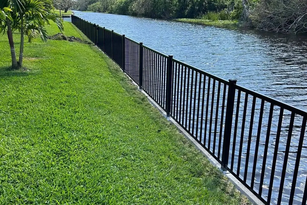 Black fence along a riverside lawn