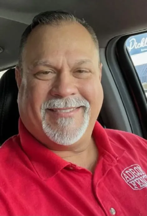 Smiling man in a car wearing red shirt